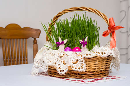 Easter theme, beautiful basket with bright green wheat and brightly colored eggs of pink and violet