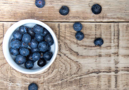 fresh bilberry berry in white cup on wooden tableの写真素材