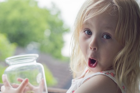 girl releases a moth from a glass jarの写真素材