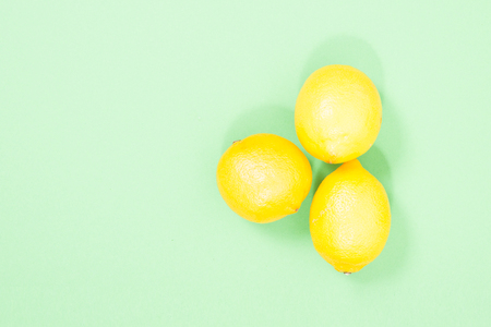 three yellow lemons on a green background.の写真素材