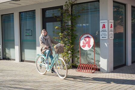 03/29/2019 Germany, the city of Kamen NRW young girl in the spring on a bicycle near the city pharmacy.のeditorial素材