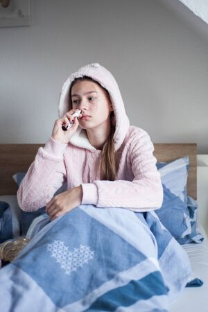 teenager girl with cold symptoms at homeの写真素材