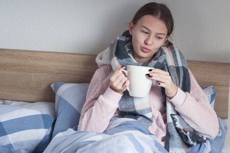 student girl lying at home in bed with flu symptomsの写真素材