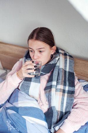Student is lying at home in bed with flu symptoms. girl takes medicineの写真素材