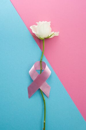 Pink ribbons with white rose on a blue background, Symbolic logo icon concept raising awareness campaign on female people living with breast cancerの写真素材