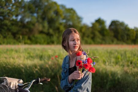 Green field background. Natural background. girl walking among green fields collecting wildflowersの写真素材