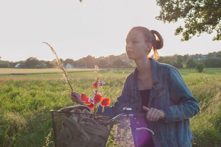 Green field background. Natural background. girl walking among green fields collecting wildflowersの写真素材