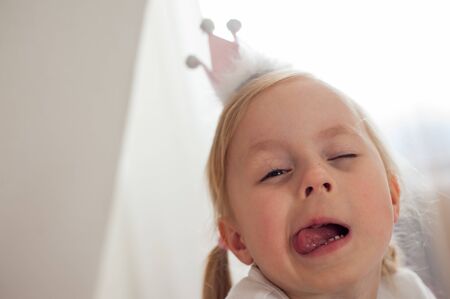 Girl with a crown on head shows tongueの写真素材