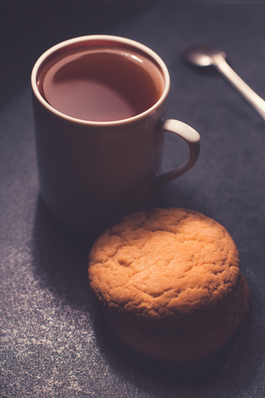 A glass cup of black tea with cookies. On a dark greyish marble background.の写真素材