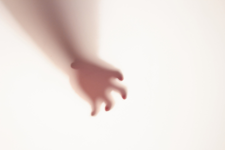 The concept of the shadow of hand behind frosted glass illuminated from behind.の写真素材