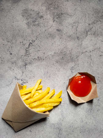 French fries in the brown paper wrapper with sauce isolated with abstract background. with copy...