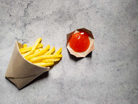 French fries in the brown paper wrapper with sauce isolated with abstract background. with copy spaceの写真素材
