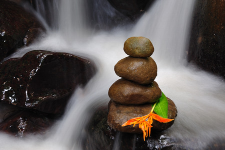 Stacked Zen stones with flower at waterfall close upの写真素材