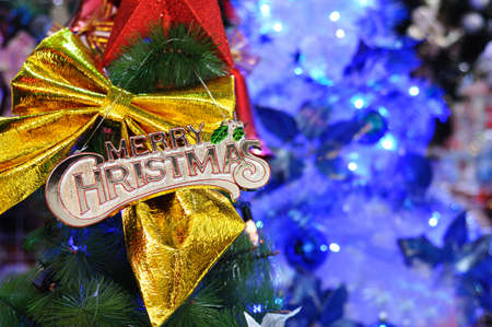 Merry Christmas with big golden ribbon and defocused christmas tree lightの写真素材