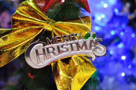 Merry Christmas with big golden ribbon and defocused christmas tree lightの写真素材