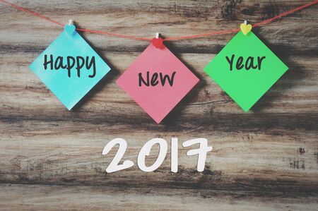 Happy new year 2017 on colorful paper with clothespin hanging on a string with wooden background,...
