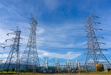 Power plant, energy power station and electric pylon, high-voltage electric tower against blue sky.