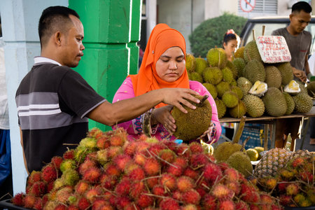 Kota Kinabalu, Malaysia - August 1, 2017: Customer choosing a fruit to buy at the fruit stall in...