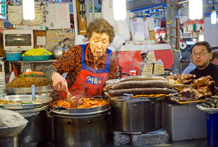 Seoul, South Korea - April 08, 2017: Woman vendor preparing a food at Gwangjang Market in Seoul. Itâs one of the ultimate places to experience traditional Korean street food and culture all one roof.のeditorial素材