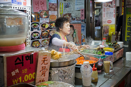 Seoul, South Korea - April 08, 2017: Woman vendor preparing a food at Gwangjang Market in Seoul. Itâs one of the ultimate places to experience traditional Korean street food and culture all one roof.のeditorial素材