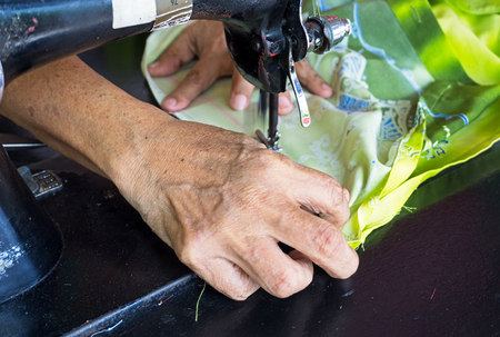 Close up of hands sewing fabric with old sewing machine.