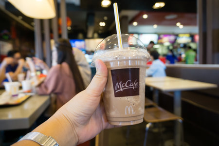 Kota Kinabalu, Malaysia - October 05, 2017: Hands holding McDonald's McCafe Iced coffee. McCafe is a...