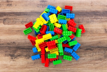 Colorful toy building blocks on wood background.