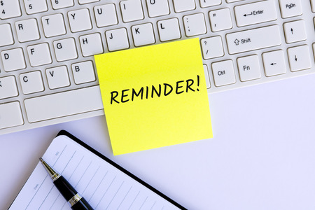 Reminder text on adhesive paper on computer keyboardの写真素材