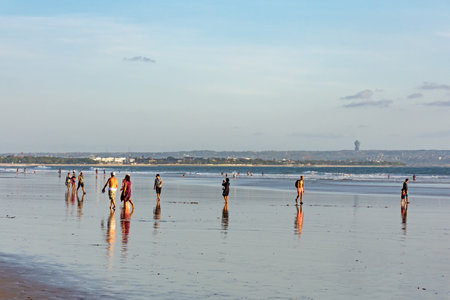 Kuta, Indonesia - September 14, 2018: Tourists and locals strolling and enjoying sunset at Seminyak beach in Bali. It is one of tourists attraction in this area.のeditorial素材