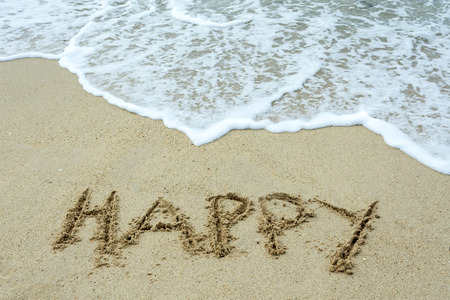 Happy word on a sand beach with waves.の写真素材