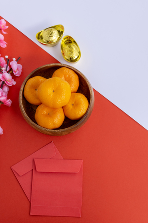 Chinese New Year Background - Cherry Blossom, Mandarin Orange, Red Envelop and Golden Ingots on dual tone background red and white.の写真素材