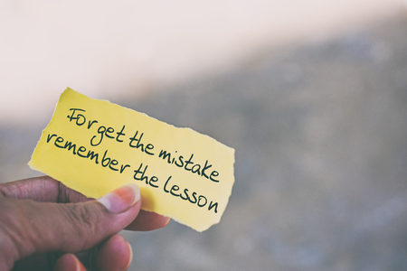 Inspirational quote on piece of paper - Forget the mistake remember the lesson.の写真素材