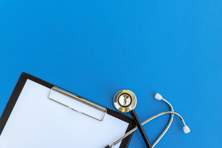 Stethoscope and clipboard on blue background, health and medical conceptの写真素材