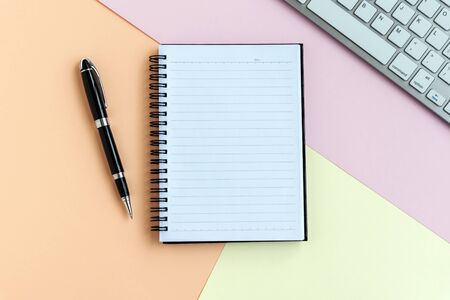 Notepad, pen, computer keyboard on top of pastel colored backgroundの写真素材