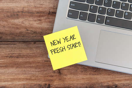 New year fresh start text on yellow adhesive paper note on top of laptop