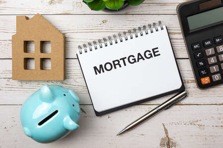 Mortgage text on note pad with piggy bank, house model and calculatorの写真素材