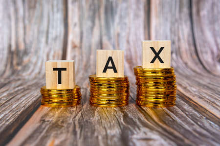 Tax Text On Wood Block On Top of Stack Of Coinsの写真素材