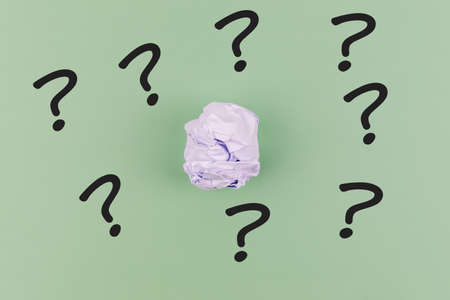 Crumpled paper ball with question mark on green backgroundの写真素材