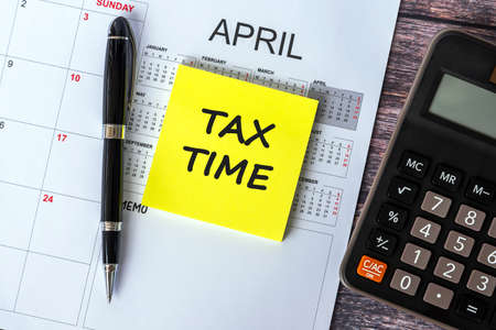 Tax Time text on adhesive note with calculator and April calendarの写真素材