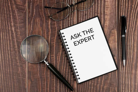 Ask the expert text on note pad with calculator and pen on wood background business and financial conceptの写真素材