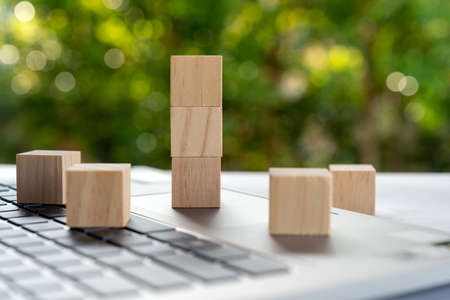 Three stack of wood block on top of laptopの写真素材