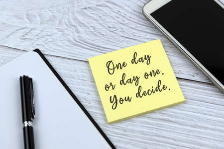 Yellow adhesive note with inspirational quotes - One day or day one.  You decide.の写真素材