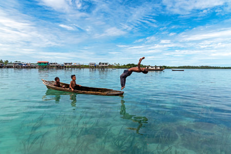 Semporna, Malaysia - August 29, 2022: Sea gypsy boy back flip from the boat. Sea gypsy is a nomadic ethnic minority live on the waters off Southeast Asia.のeditorial素材