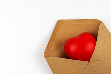 Close up of heart shape in a brown envelope on white background