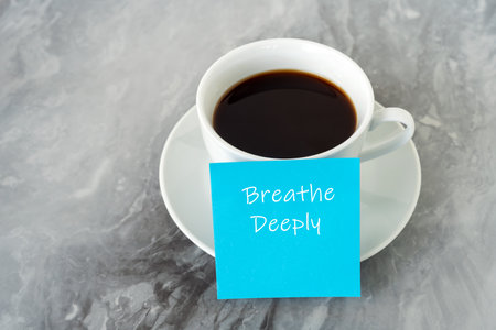 Cup of coffee and adhesive note with text Breath deeplyの写真素材