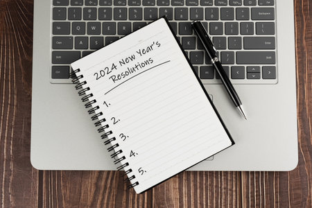 Laptop and Notepad with text - 2024 New Year's Resolutions
