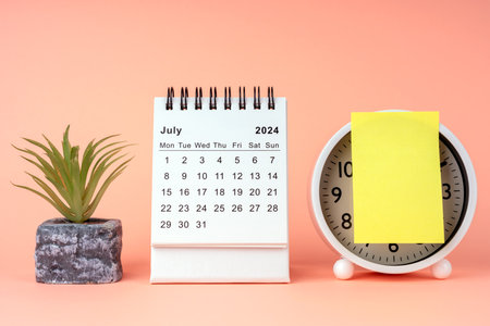 July 2024 desk calendar with adhesive note and alarm clockの写真素材