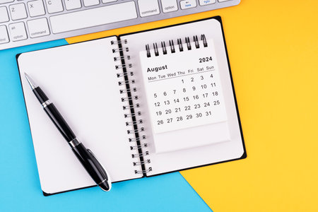 August 2024 calendar, notepad, pen and computer keyboardの写真素材