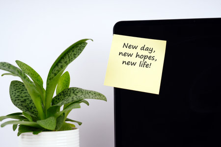 Adhesive note on a laptop screen with text - New day, new hopes, new life