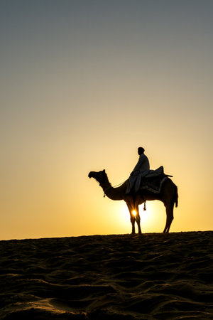 Indian Man Riding Camel During Sunrise at Thar Desert in Rajasthan, India